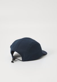 Navy blue cap made of lightweight, textured fabric with a curved brim and perforated design; features an adjustable strap at the back.