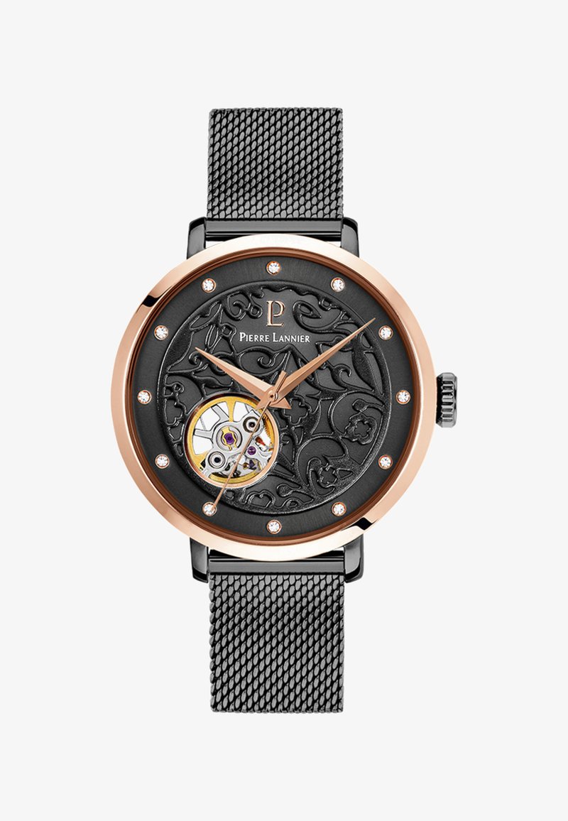 Okrągły zegarek z czarną wzorzystą tarczą, złotymi akcentami i przezroczystym mechanizmem mechanicznym. Posiada czarny metalowy pasek siateczkowy.