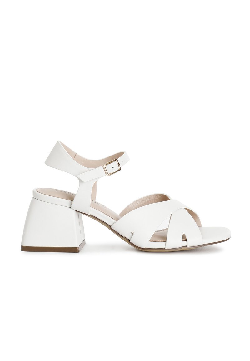 Witte blokhak sandalen met gekruiste banden, een enkelgesp en een soepele leren afwerking. Ontworpen voor comfort en stabiliteit.