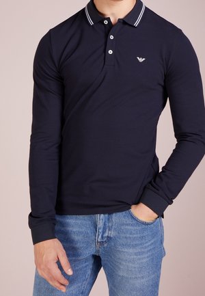 Marineblaues Polohemd mit langen Ärmeln aus Baumwollmischung, mit weiß gestreiftem Kragen, Dreiknopfleiste und kleinem Logo auf der Brust.