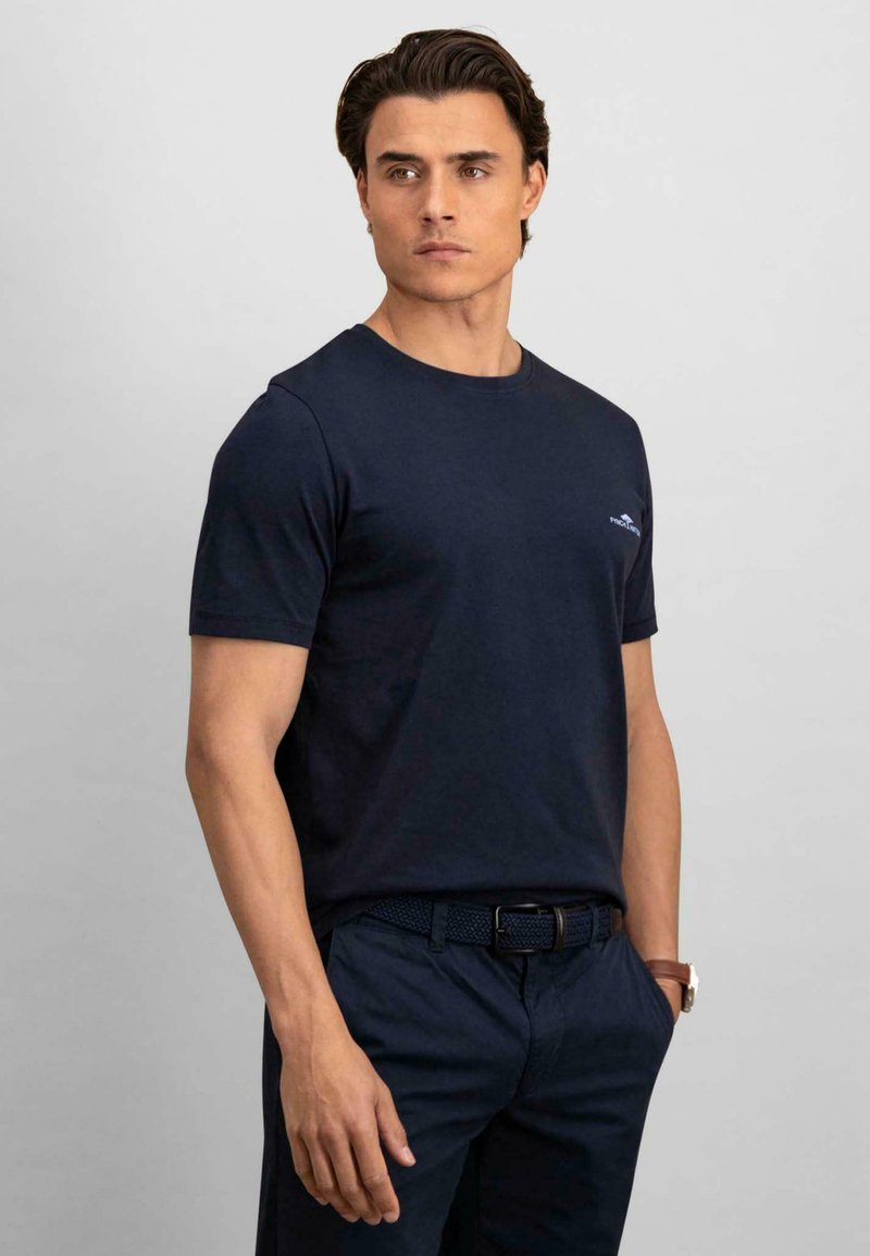 Tricou de bumbac cu mânecă scurtă, de culoare bleu marin, având un guler rotund și un mic logo pe partea stângă a pieptului. Textură netedă.