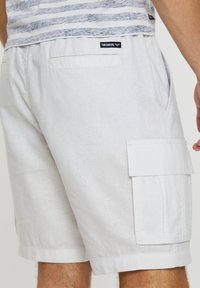 Bermudas cargo de color gris claro, confeccionadas en una mezcla de lino, que cuentan con un bolsillo parche en el lateral y una etiqueta con la inscripción "THREADBARE" en la parte posterior.