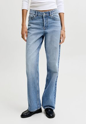 Isik kannab helesiniseid sirge säärega teksapükse, valget keha järgivat pika varrukaga pluusi, musti mokasiine, vasakul käel sõrmust ja paremal randmel käevõru.