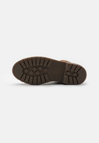 Suela de bota de goma marrón con un patrón de relieve texturizado y un detalle de logo, diseñada para ofrecer tracción y durabilidad.