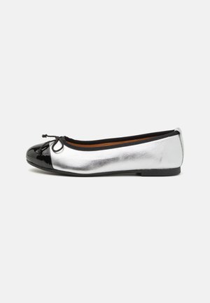 Ballet flats featuring a metallic silver leather upper and a glossy black patent toe cap, with a bow accent on the front. Flat sole.