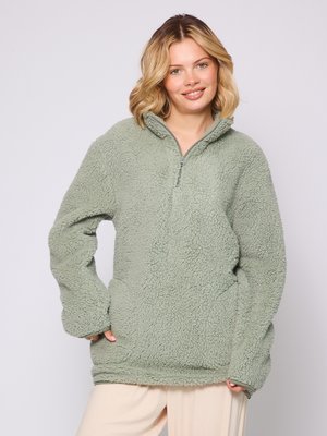 Fleece-Pullover in blassgrün mit einem halben Reißverschluss am Ausschnitt und seitlichen Taschen. Strukturierter, weicher Stoff mit lockerer Passform und langen Ärmeln.