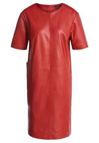 Robe en cuir rouge à manches courtes, col rond et coutures minimales. Présente une coupe droite et des poches latérales pour une fonctionnalité accrue.