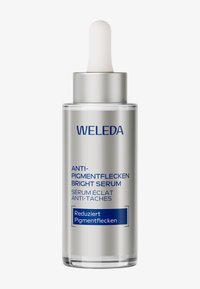 Weleda Serum Rozjaśniające Anty-Pigmentowe w przezroczystej, srebrnej szklanej buteleczce z kroplomierzem. Niebieski tekst na etykiecie podkreśla szczegóły produktu.