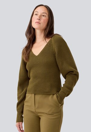 Pull en maille vert olive avec un décolleté en V profond, texture côtelée et manches bouffantes. Assorti à un pantalon ajusté de la même couleur.
