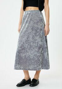 Grå fløjls maxi nederdel med en glat tekstur, elastisk talje og subtil marmorering, parret med sorte loafers.