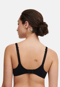 Svart BH med justerbara axelband och hak- och ögllåsning baktill. Slätt tyg med minimalistisk design och inga synliga mönster.