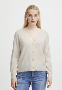 Beige v-neck cardigan with a soft texture, featuring three buttons down the front and ribbed cuffs, paired with blue jeans.
