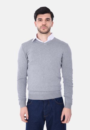 Maglione grigio lavorato a maglia con scollatura a V, orlo e polsini a coste, indossato sopra una camicia bianca con colletto. Presenta una texture liscia e un design aderente.