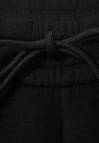 Schwarzer elastischer Bund mit Kordelzug, hergestellt aus weichem Stoff. Die Textur ist glatt, mit Nähten und Raffungen entlang des Bundes.