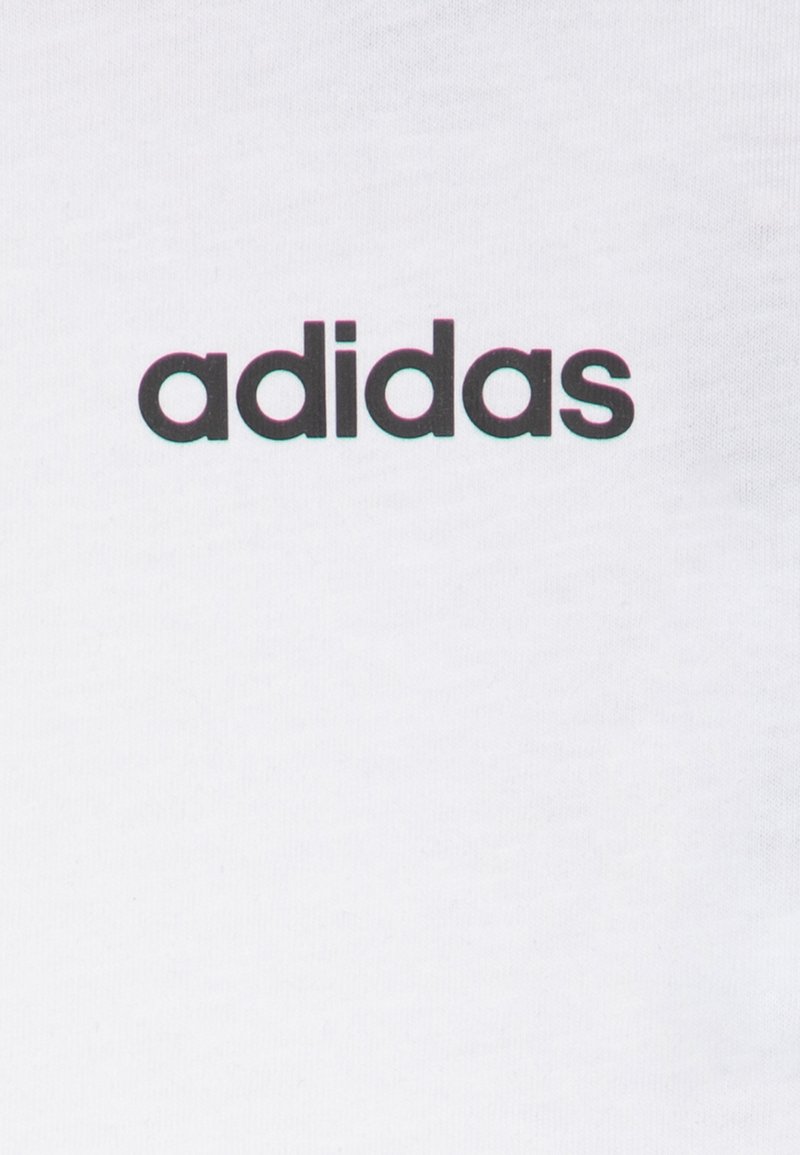 T-shirt en coton blanc avec un grand texte noir "adidas" imprimé au centre, possédant une texture lisse et un design minimaliste.