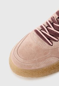 Baskets en daim rose clair avec des lacets marron. Présente des détails cousus et une semelle extérieure en caoutchouc gomme avec une surface texturée.