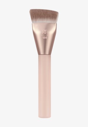 Pinceau de maquillage avec des poils denses et inclinés, une virole en or rose et un manche beige, marqué "RT 135" sur la virole.