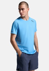 Heledsinine spordisärk, mis on valmistatud niiskust juhtivast kangast, lühikeste varrukatega ja ümarate kaelustega. Ees on trükitud logo.