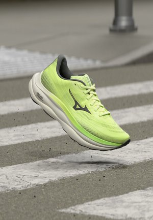 Chaussure de running jaune néon avec logo noir et semelle blanche flottant au-dessus d'un passage piéton sur une surface de rue.