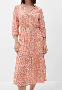 Kwiecista sukienka midi w pomarańczowo-białym kolorze, z dekoltem w kształcie litery V, wykończona rękawami do łokcia, elastycznym pasem oraz warstwowym dołem. Wykonana z miękkiej tkaniny. 