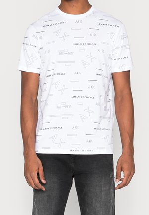 Valkoinen t-paita, jossa on hajallaan mustaa tekstiä ja graafisia suunnitelmia. Lyhyet hihat, pyöreä pääntie ja sileä puuvillakangas.