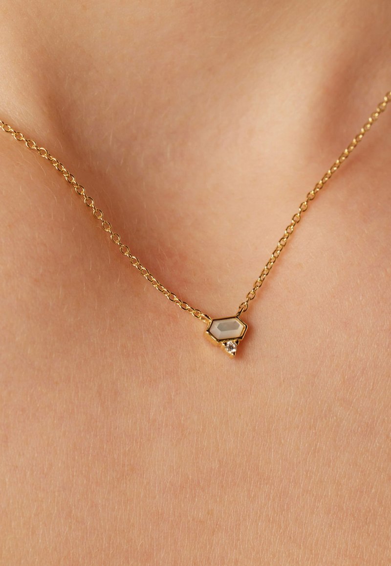 Gouden ketting met een hexagonaal hanger die een semi-transparante steen en een kleine heldere edelsteen accent op een fijne ketting bevat.