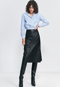 Niebieska i biała paskowana koszula z guzikami, czarna skórzana spódnica midi, czarne wysokie buty z fakturą, dopasowany krój, gładkie tekstury.