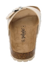 Witte instapsandaal met een metalen gespaccent, kurken middenzool en gestructureerde bruine voetbed. Merkennaam "palado" zichtbaar van binnen.