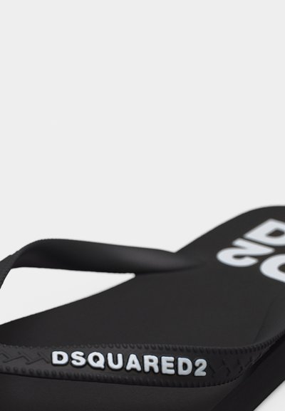 Sandale tong noire avec le logo DSQUARED2 sur la bride et un grand texte blanc sur la semelle, présentée sur un fond blanc uni.