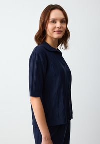 Polo a maniche corte di colore blu navy, con texture a coste e dettagli a strisce diagonali. Realizzato in un tessuto morbido e leggero.