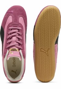 Rosa Wildledersneaker mit schwarzen Akzenten, ausgestattet mit einer strukturierten Gummisohle, Schnürung vorne und goldener Markenkennzeichnung an der Seite.