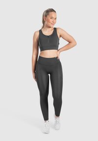 Leggings neri a vita alta e un reggiseno sportivo coordinato con zip frontale, realizzati in tessuto liscio ed elastico, progettati per l'abbigliamento sportivo.