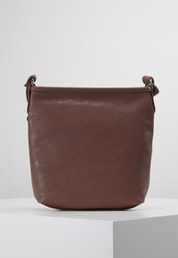 Braune Ledertasche im Eimer-Stil mit glatter Textur, Reißverschluss oben und einem abnehmbaren Tragegurt. Minimalistisches Design ohne sichtbare Hardware-Details.