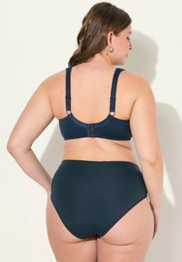 Navyblauwe bikini set met stevige schouderbanden en verstelbare haakjes. Hooggetailleerde broek met een gladde textuur en minimale details op de stof.