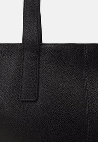 Borsa a spalla in pelle nera con una finitura testurizzata, caratterizzata da una forma rettangolare semplice e manici verticali robusti. Cuciture a vista.