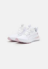 Un par de zapatillas deportivas blancas con suelas y acentos rosa claro, atadas con cordones, colocadas una al lado de la otra sobre un fondo blanco.