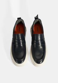 Instapschoenen van marineblauw leer met een contrasterende witte zool. Voorzien van een gladde textuur en een decoratieve band over de voorkant.