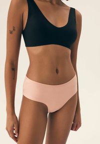 Czarny gładki materiałowy biustonosz typu bralette oraz jasnoróżowe wysokie szorty chłopięce, oba o minimalistycznym wzornictwie, bez widocznych elementów metalowych lub wzorów.