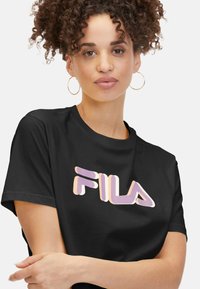 Camiseta negra de manga corta con un gran logo de FILA en colores púrpura y naranja. Tejido suave y corte relajado.
