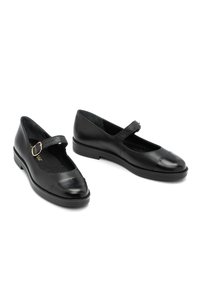 Zapatos Mary Jane de cuero negro con puntera redonda y suela plana. Presentan una única correa ajustable con una hebilla dorada. Textura suave.
