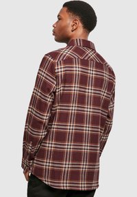 Flanellhemd in Burgunderrot und Creme mit Karomuster, langärmlig, mit Button-Down-Kragen und abgerundetem Saum. Verfügt über eine weiche Textur.