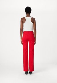 Røde skreddersydde bukser med rett ben, høy midje, belteholdere og to baklommer, kombinert med en hvit ribbestrikket tanktopp.