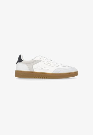 Sneaker bianco low-top con dettagli in camoscio beige, suola in gomma, linguetta nera sul tallone e marchio "ARIGATO" su lato e suola.