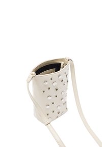 Beżowa torebka crossbody z ekoskóry z srebrnymi ćwiekami, zamknięciem na zamek i regulowanym paskiem. Teksturowana powierzchnia z okrągłymi wycięciami.