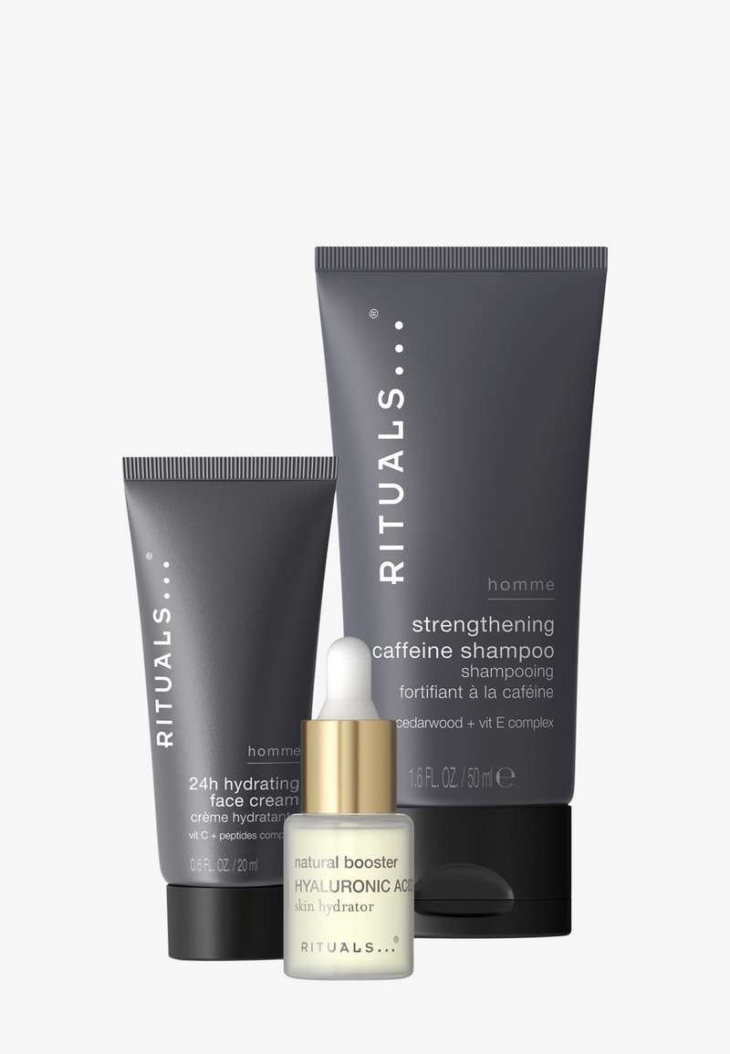 Kolme kosmetiikkatuotetta: yksi tummanharmaa tuubi, jossa lukee "24h Hydrating Face Cream", suurempi harmaa tuubi "Strengthening Caffeine Shampoo" -shampoolle ja valkoinen tiputuspullo, jossa on kultakorkki ja teksti "Natural Booster Hyaluronic Acid".