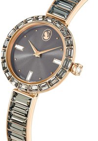 Złoty różowy zegarek z szarym cyferblatem, prostokątnymi znacznikami godzin i obrączką zdobioną prostokątnymi kamieniami; bransoleta stylizowana na połączone segmenty.