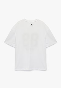 Hvid kortærmet t-shirt med rund hals; struktureret stof; har et trykt design på ryggen med tal og et lille logo nær halsen.
