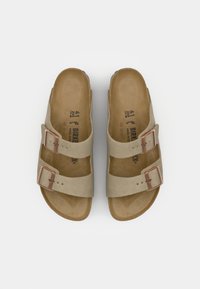 Sandales beiges avec deux brides réglables et boucles en ton cuivre. Semelle intérieure douce avec une texture lisse, étiquetée avec la taille 41 et le nom de la marque.
