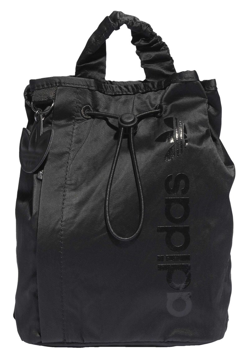 Black drawstring bag made of nylon with a glossy black "adidas" logo and a textured finish. Features a scrunched handle and attached logo tag.