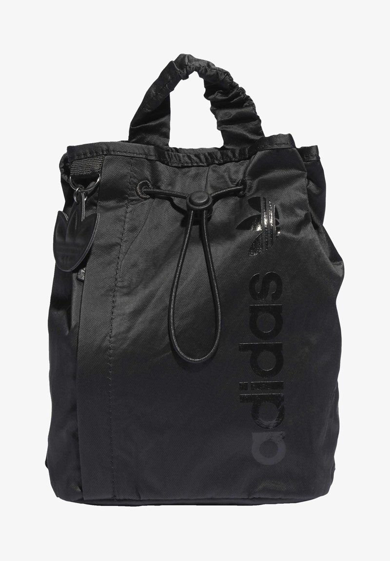 Black drawstring bag made of nylon with a glossy black "adidas" logo and a textured finish. Features a scrunched handle and attached logo tag.